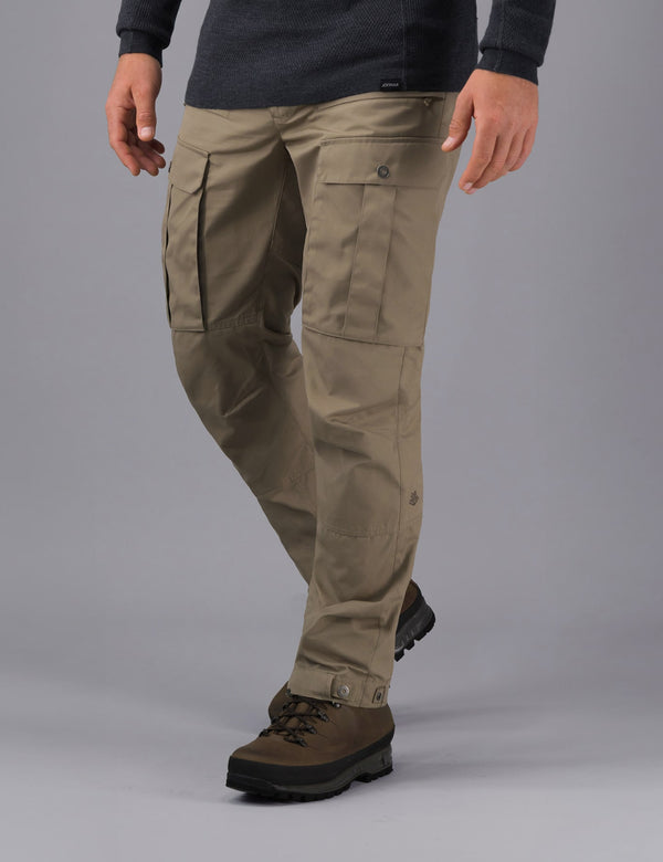 Person wearing sand Torv waxed trekking trousers on a grey background